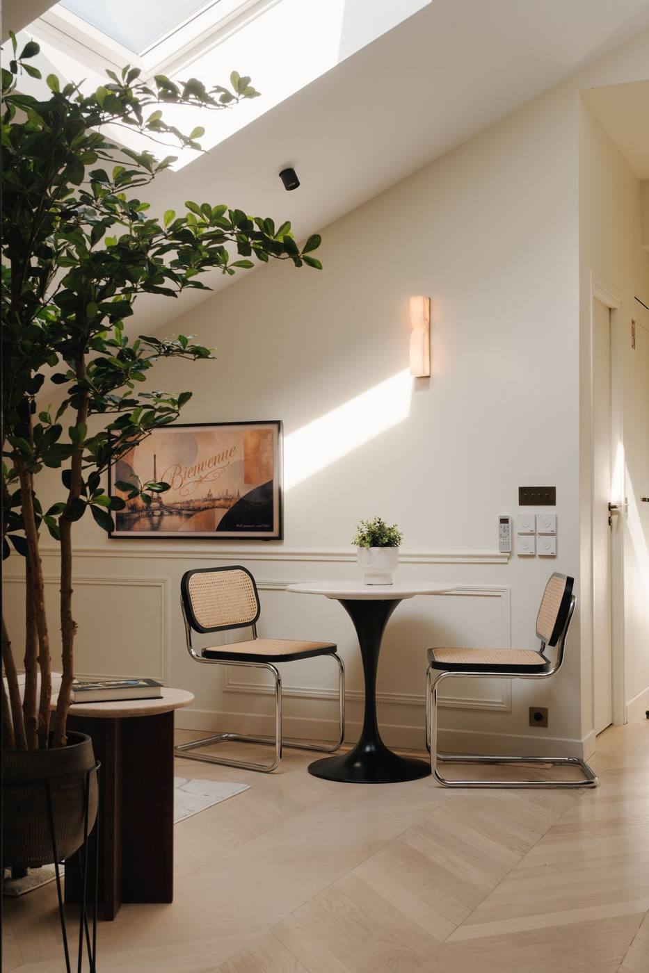 Coin salon sous verrière de toit, table ronde et chaises cannées