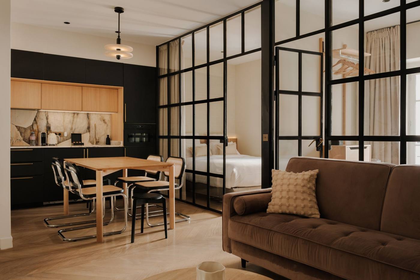 Suite 01 : séjour, table de six et cuisine noire en fond