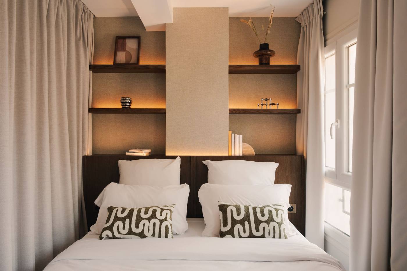 Chambre aux niches éclairées et coussins à motif géométrique